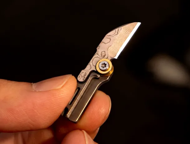 Tikzer G11: Micro-cuțitul EDC din titan și oțel Damasc de mărimea unui deget
